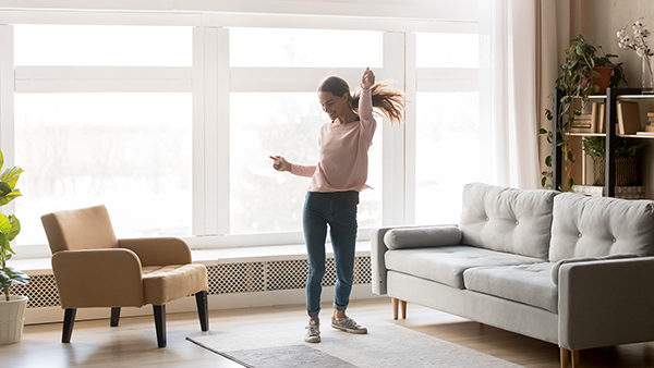 Happy carefree young woman dancing alone having fun at home